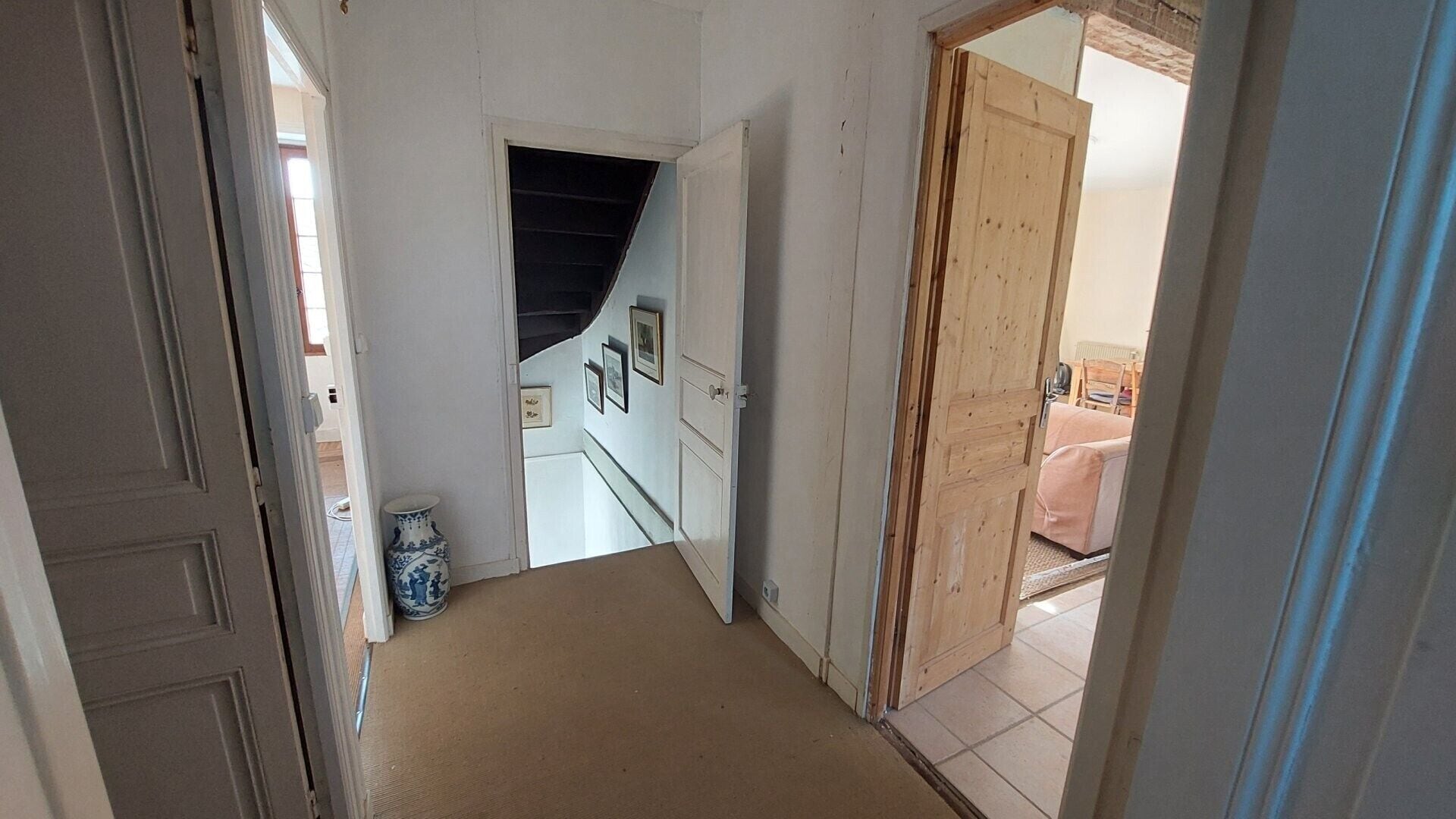 Ein Flur mit einer Tür zu einem Schlafzimmer, das ein Bett und einen Sessel bietet.