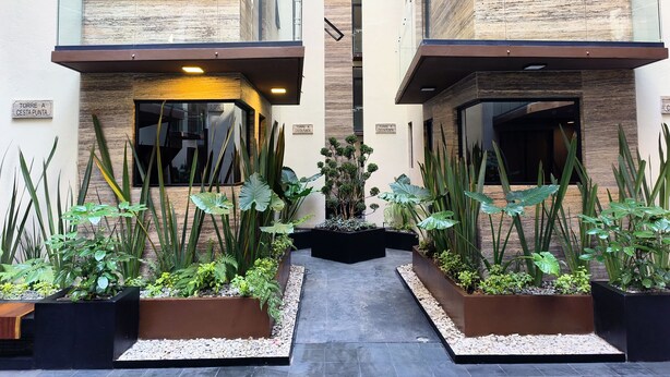 A modern building with two balconies, a central garden area, and a sign reading "TORRE A CESTA PUNTA".