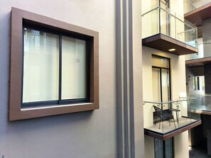 Un edificio moderno con un amplio ventanal, un balcón de cristal y un diseño limpio y minimalista.