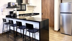 A modern kitchen with a central island, bar stools, a built-in oven, and a refrigerator.