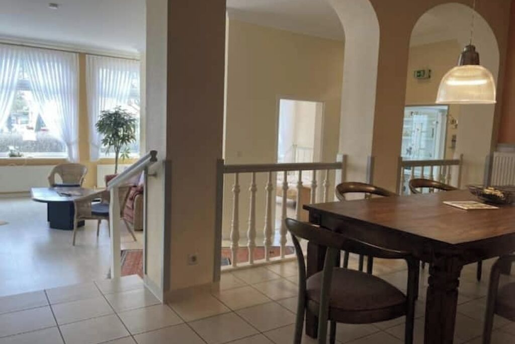 A spacious living area with a dining table, chairs, and a staircase leading to an upper level.