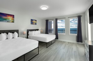 A hotel room with two beds, a large window with curtains, a painting, and a view of the sea. - New Snowbird 3BR Condo On The Boardwalk + 100 Dollar Resort credit (Myrtle Beach)