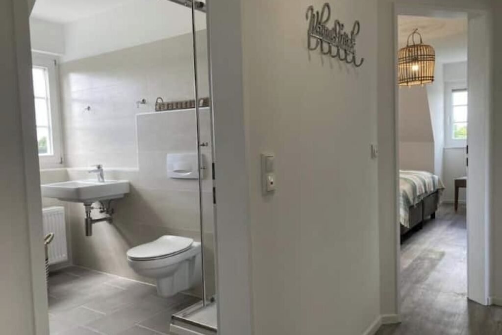 A modern bathroom with a glass shower enclosure, a toilet, and a sink.