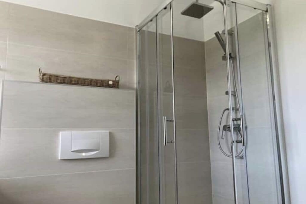 Eine gläserne Dusche mit Bedienfeld und Handtuchhalter darüber.