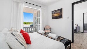 Een hotelkamer met een bed, een stoel, een schilderij en uitzicht op het groen.