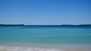 A beach with clear turquoise water and distant landforms. - Husky Beach Pad by Book Jervis Bay - Walk to the beach (Huskisson)