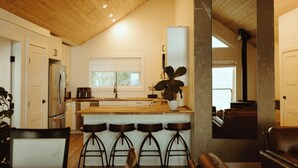 Une cuisine moderne avec un plafond en bois, des armoires blanches et un grand îlot central doté de tabourets de bar.
