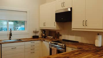 Een keuken met witte kastjes, een oven van roestvrij staal en houten aanrechtbladen.