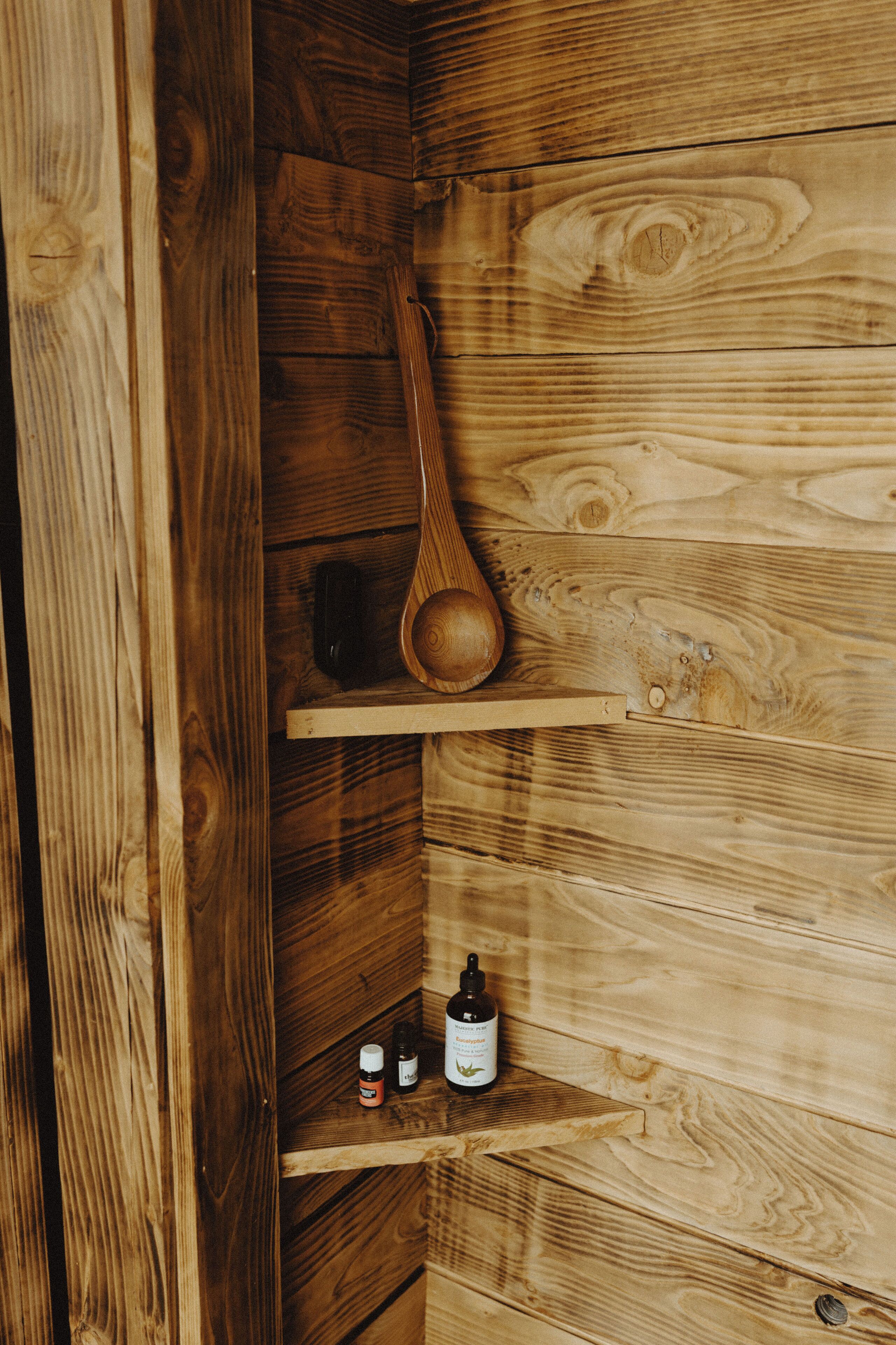 Interior de madera con estantes que sostienen una cuchara de madera y botellas.