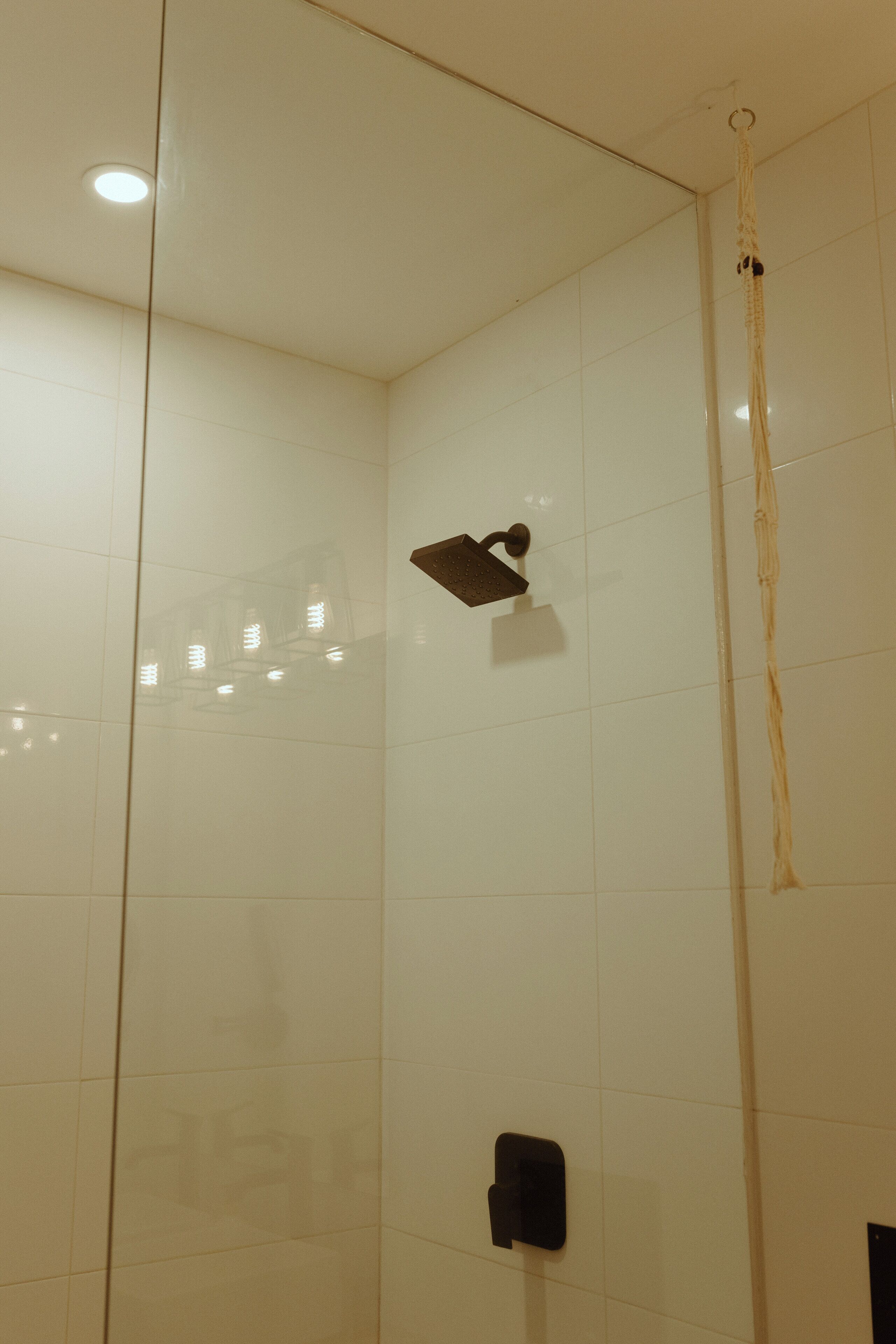A shower with a handheld showerhead and a vertical rain showerhead.