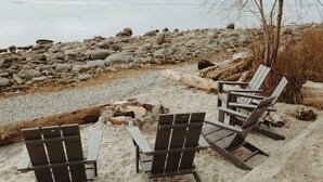 Ein Strand mit Holzstühlen und einem Baumstamm.