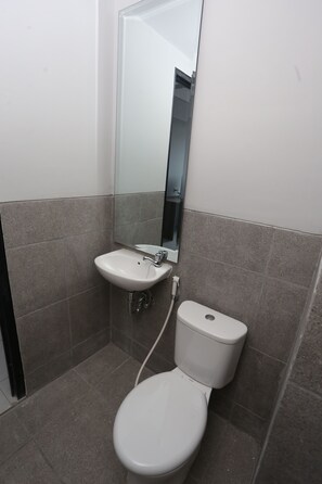 Une salle de bain avec un lavabo blanc, des toilettes et un miroir au-dessus du lavabo.
