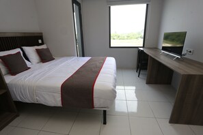 Une chambre d’hôtel moderne avec un grand lit, un bureau et une télévision.