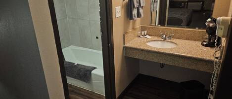 Een badkamer met een wastafel, spiegel en douche.