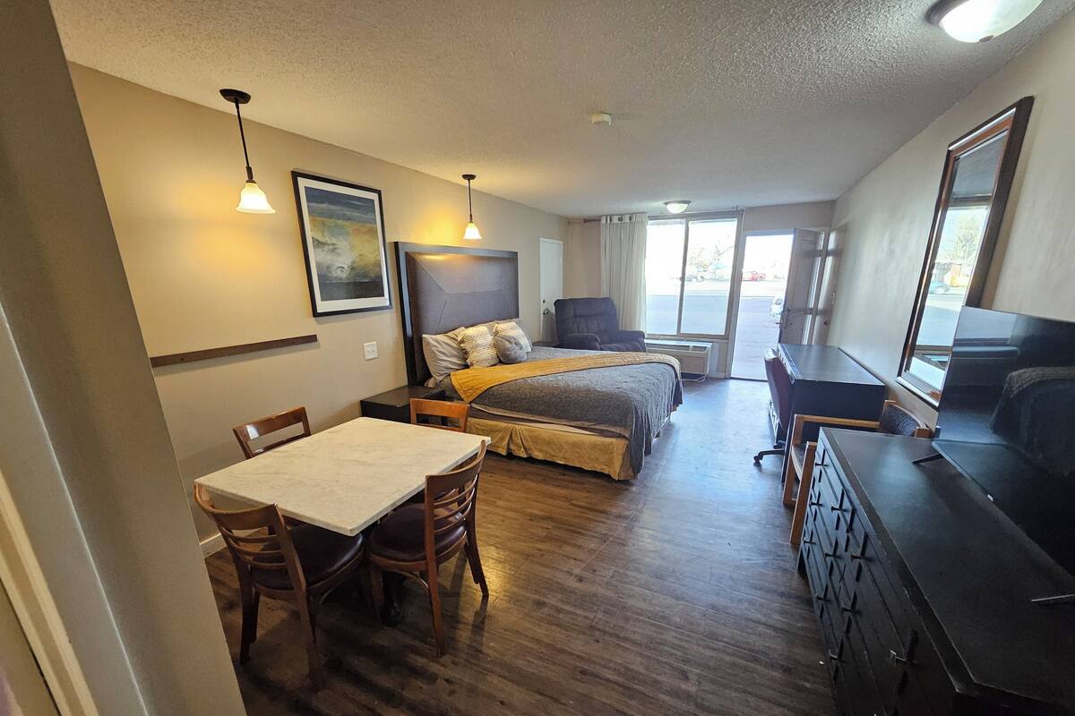 A compact hotel room with a bed, a desk, a chair, and a TV.