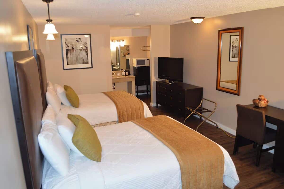 Une chambre d’hôtel avec deux lits, un bureau, une chaise, une télévision et un four à micro-ondes.