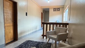 Un'ampia hall con una porta in legno, un tappeto scuro e un'area salotto con poltrone.
