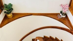A wooden spiral staircase with a landing area featuring potted plants. - Tia Vahine - Boutique Hôtel Ivato (Antananarivo)