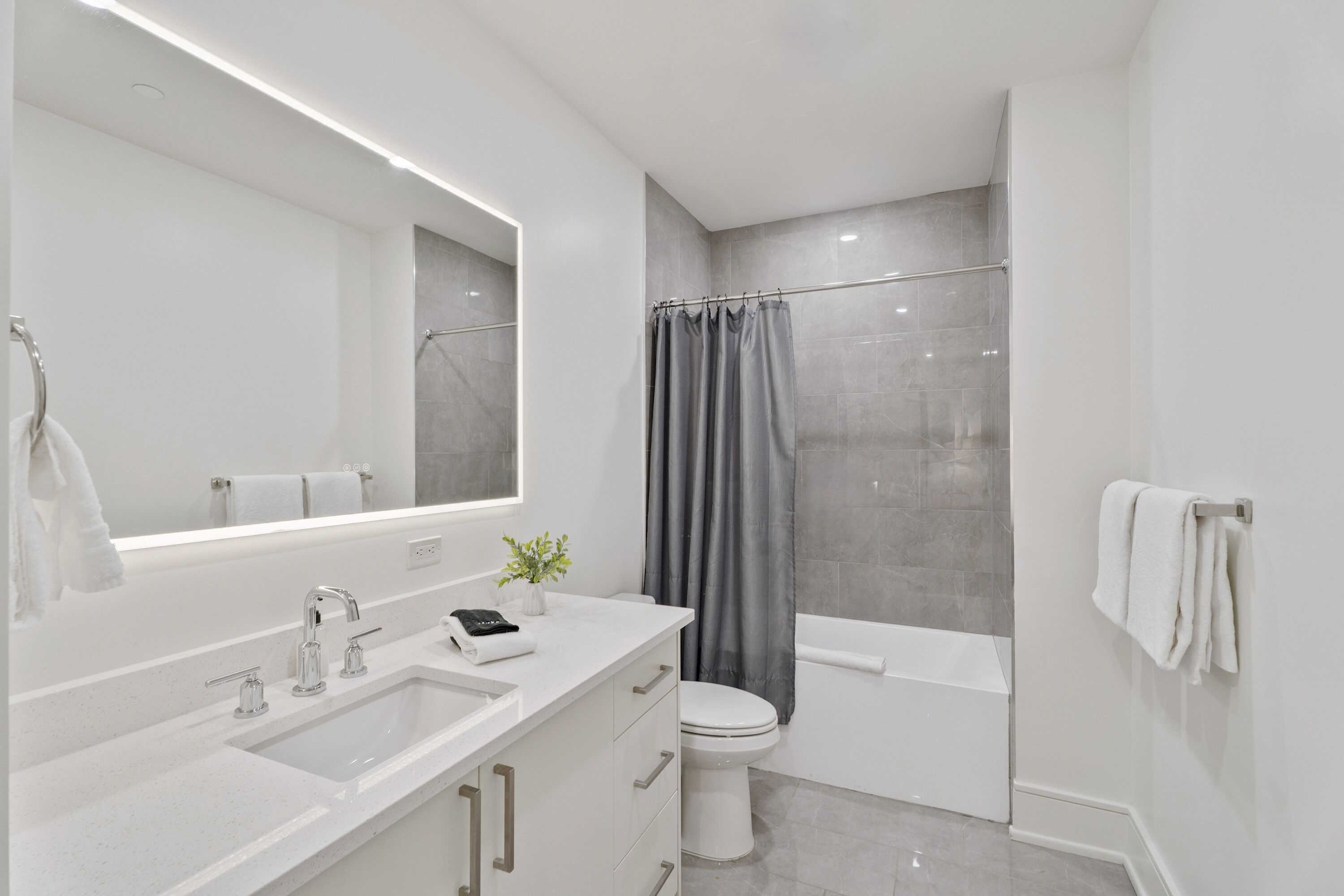 A modern bathroom with a white sink, a toilet, a bathtub, and a shower curtain.