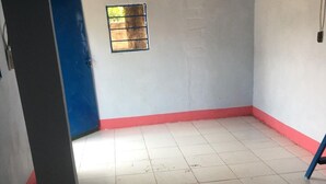 Une pièce avec un sol carrelé, une porte bleue et une petite fenêtre.