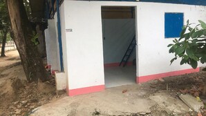 Un petit bâtiment d’un seul étage, à l’extérieur blanc et à la base rouge. Une fenêtre bleue se trouve sur le côté droit, et une échelle est appuyée contre le mur à l’intérieur.