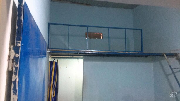 Une pièce avec un mur bleu, une étagère en métal et une porte.
