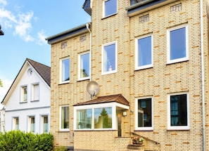 A multi-story residential building with a brick facade, multiple windows, and a satellite dish.