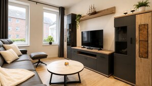 Ein modernes Wohnzimmer mit einer Couch, einem Couchtisch, einem Fernseher und einem Schrank.
