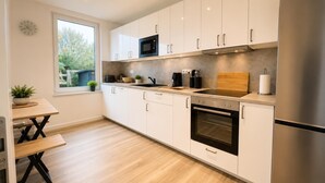 Eine moderne Küche mit weißen Schränken, einem Edelstahl-Kühlschrank, einer Mikrowelle und einem Backofen.