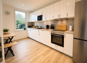 A modern kitchen with white cabinets, a stainless steel refrigerator, a microwave, and an oven. - House Deichlust Whg.1,Strichweg 165, 27476 Cuxhaven-Döse (Cuxhaven-Döse)