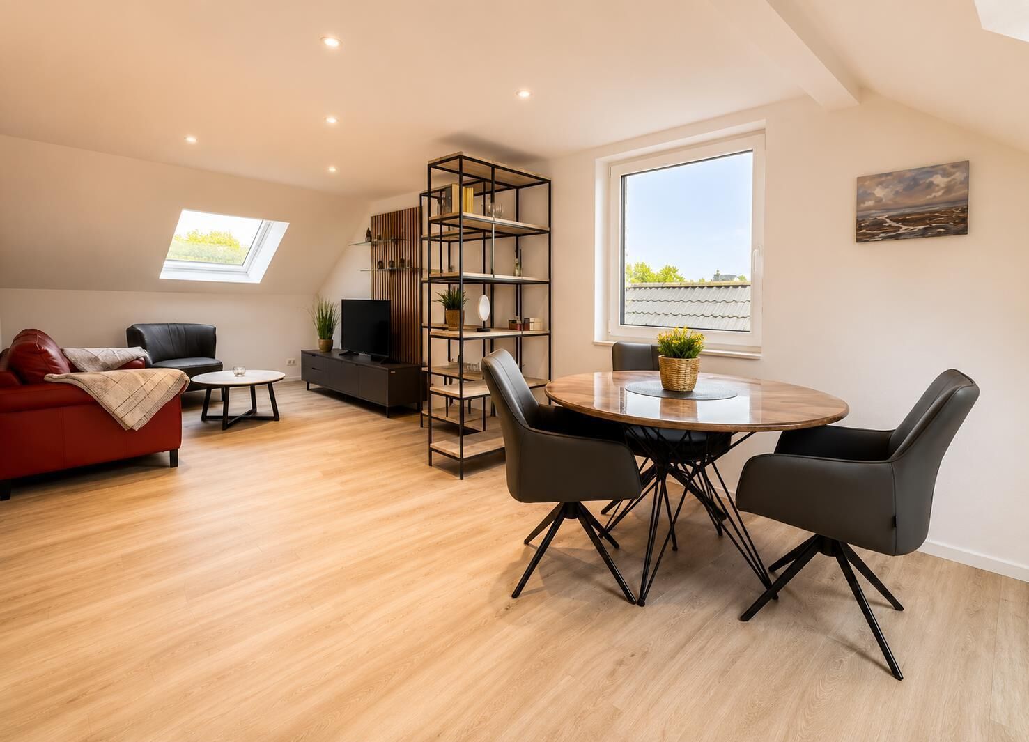 A modern living room with a red sofa, a TV, a bookshelf, a dining table with chairs, and a large window with a view.