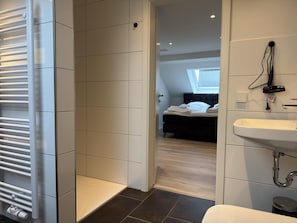 Ein modernes Badezimmer mit Waschbecken, Handtuchhalter und Duschbereich.