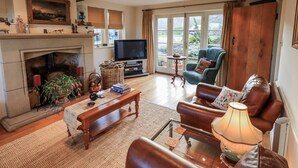 A cozy living room with a fireplace, a television, and comfortable seating. - Orchard House (Leyburn)