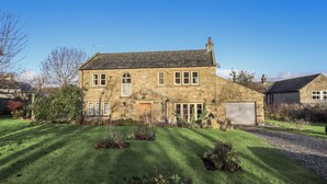 A two-story stone house with a large front lawn, a garage, and a chimney. - Orchard House (Leyburn)