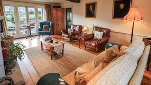 A spacious living room with a sofa, armchairs, a coffee table, and a fireplace. - Orchard House (Leyburn)