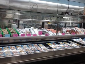 Vitrina refrigerada en un supermercado con diversos productos del mar y etiquetas de precio.