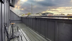 A balcony with metal chairs and a small table, overlooking a residential area with houses and power lines. - Soothing 1-bedroom condo with AC in vibrant Vancouver (Vancouver)
