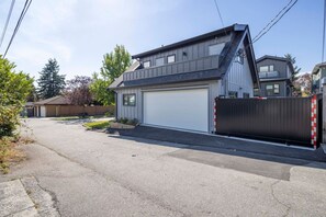 Een woonhuis met twee verdiepingen, een garage, een oprit en een zwart hek met reflecterende strepen.