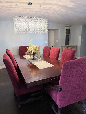 A dining room with a wooden table, red upholstered chairs, a decorative centerpiece, and a unique ceiling light fixture. - Spacious Riverfront Getaway 5 beds 3.5 bath & views (Sacramento)