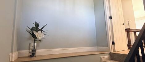 A staircase with a handrail, a wall-mounted vase with flowers, and a ceiling light fixture.
