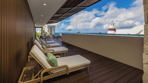 A wooden deck with lounge chairs and a view of the ocean. - 3 Bedroom Condo 2 Private Balconies, Pool, Gym in Downtown Cozumel. (Cozumel)