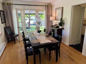 A dining area with a table set for four, surrounded by chairs, with a view of the outdoors through a glass door. - Black Walnut House @ Pioneer Park + W2 Central (Walla Walla)