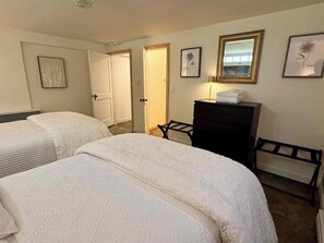 A hotel room with two beds, a dresser, a desk, and a chair. There are doors leading to other rooms. - Black Walnut House @ Pioneer Park + W2 Central (Walla Walla)
