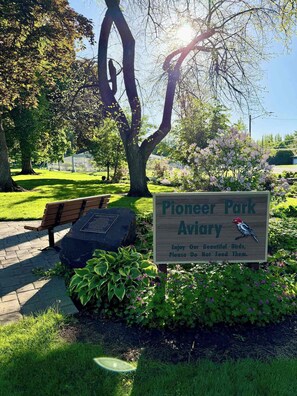A park sign for Pioneer Park Aviary with a bench and greenery in the background. - Black Walnut House @ Pioneer Park + W2 Central (Walla Walla)