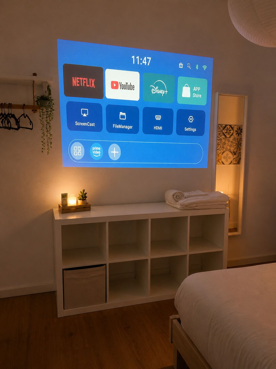 Pantalla digital en una habitación de hotel con cama, mesita de noche y estante en la pared.