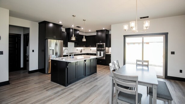 A modern kitchen with dark cabinets, stainless steel appliances, and a central island. - Minutes from the airport, beautiful new Bentonville home! (Bentonville)