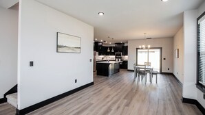 A modern kitchen with dark cabinetry, a central island, and pendant lighting. - Minutes from the airport, beautiful new Bentonville home! (Bentonville)