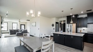 A modern kitchen with dark cabinets, a stainless steel refrigerator, and a central island. - Minutes from the airport, beautiful new Bentonville home! (Bentonville)