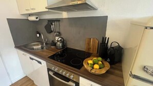 Una cocina compacta con estufa, horno y un bol de madera lleno de limones y limas en la encimera.