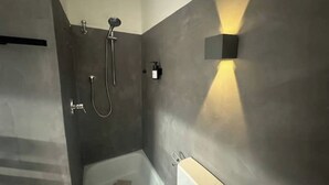 Un baño moderno con ducha, bañera y una lámpara en la pared.